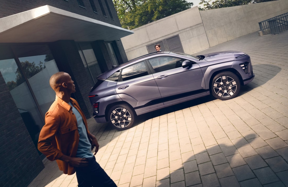 A personal walking by a new Hyundai KONA Electric as someone starts to get inside.