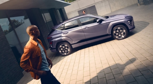 A personal walking by a new Hyundai KONA Electric as someone starts to get inside.