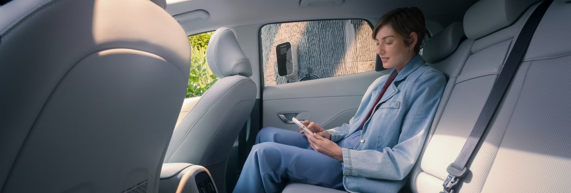 A person on their mobile phone whilst sat inside the interior of a new Hyundai KONA Electric.