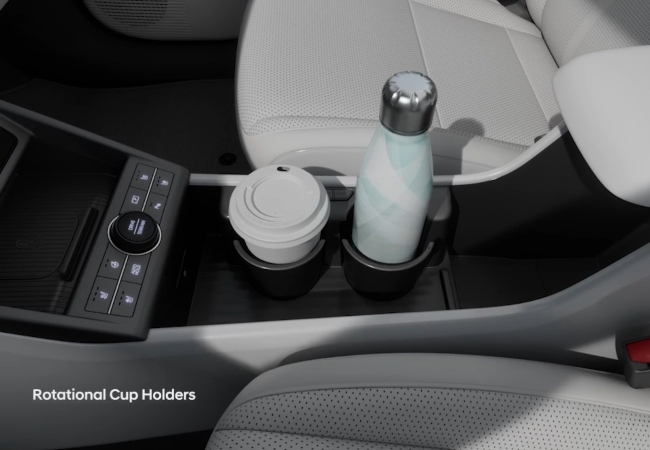 A close up shot of a centre console holding a coffee cup and water bottle.