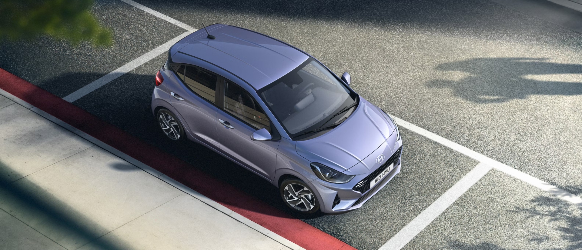 Angled top down shot of a new Hyundai i10 parked on the side of a road.