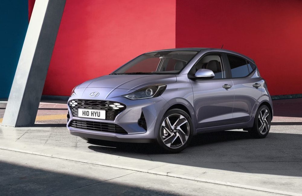 Angled front shot of a new Hyundai i10 parked on the side of the road, showing off the LED lighting and unique design.