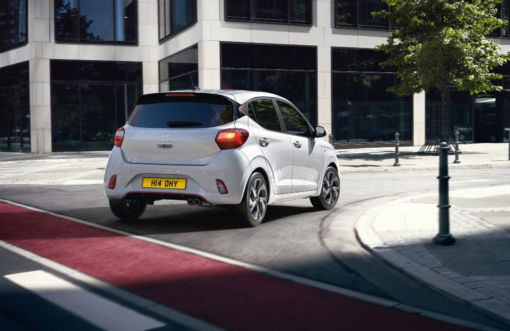 Rear shot of a white Hyundai i10 N Line driving at speed around a city street corner.