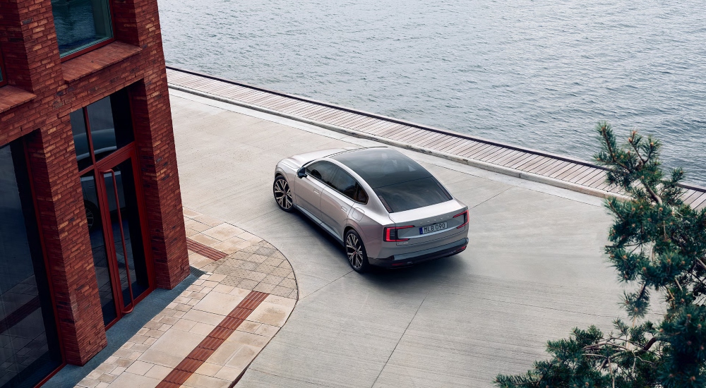 Aerial view of a Volvo ES90 driving round a corner near the sea: Used Volvo ES90 finance