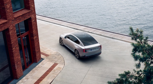 Aerial view of a Volvo ES90 driving round a corner near the sea: Used Volvo ES90 finance