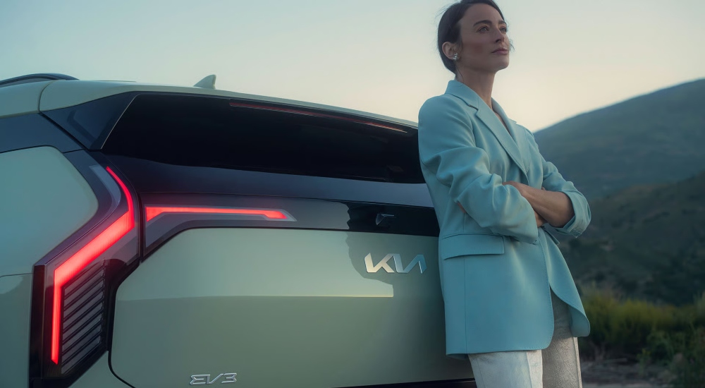 A person leaning an the rear of The Kia EV3; The New Kia EV3 for Sale