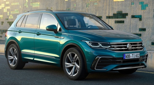 Green Volkswagen SUV parked next to a modern building.