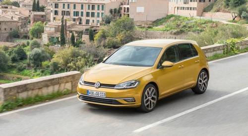 Golden yellow VW Golf driving down a country road at speed.