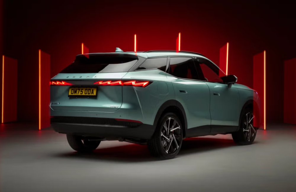 Angled rear shot of a new OMODA 7, showing off the unique rear design with a red backdrop.
