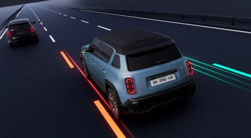 Rear shot of a new Renault 4 driving at speed down a road, showing off the safety systems.