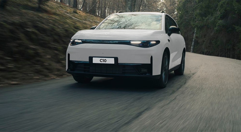 A new Leapmotor C10 Hybrid EV driving at speed down a forest road.
