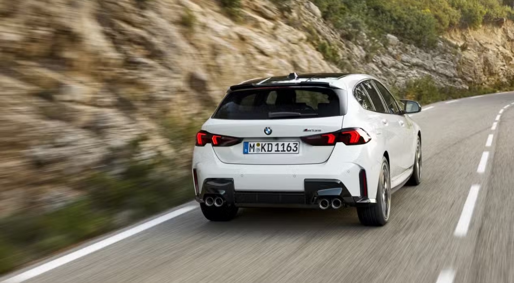 The rear of a white BMW 1 Series driving along a road; Used car BMW 1 Series