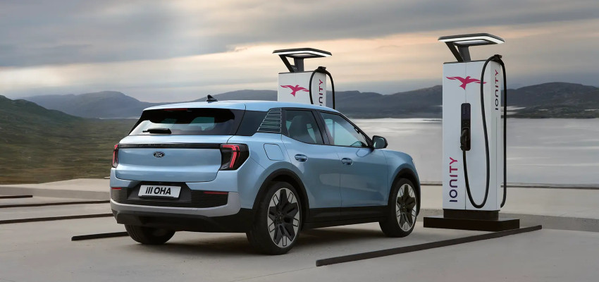 A blue Ford Explorer charges in a charging bay by water; How EVs work intro image