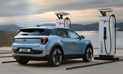 A blue Ford Explorer charges in a charging bay by water; How EVs work intro image