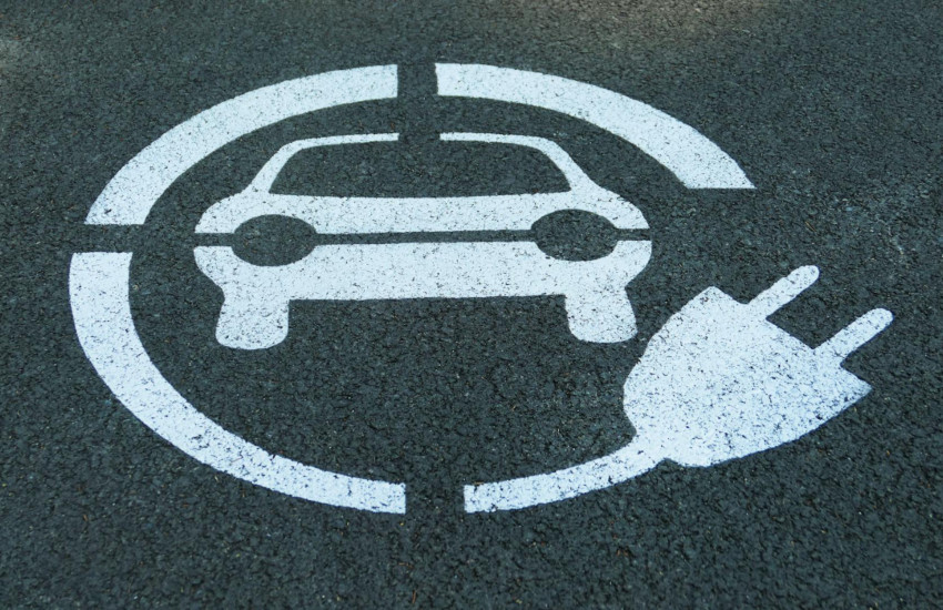 An EV charge point logo on the road; Cost to charge EV in public image