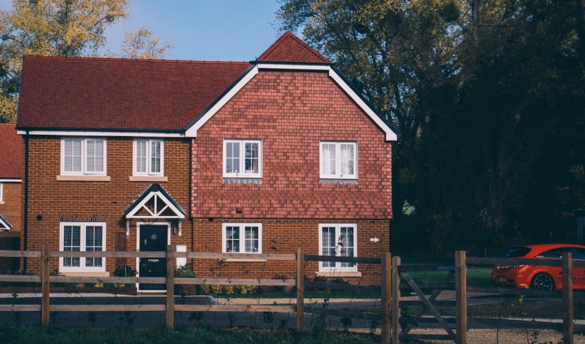 A large home with a red car outside; Property checks for EV installation image
