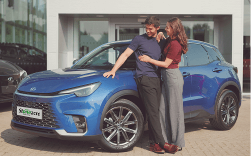 A couple stands in front of a Lexus LBX; Car finance options image.