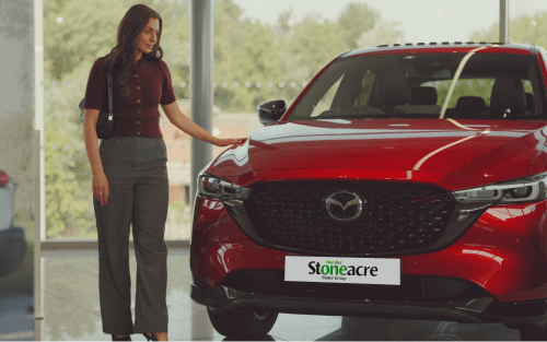 A woman stands beside a red Mazda CX-5; Car finance types image.