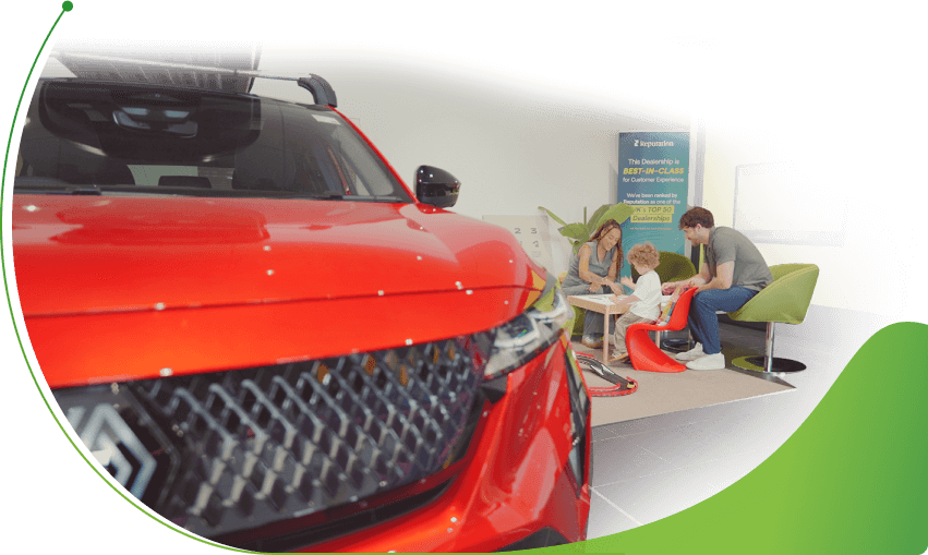 A family in a car dealer's play area besides a red Renault; 0% used cars finance image