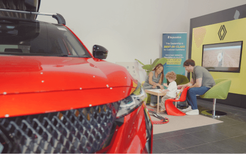 A family in a car dealer's play area besides a red Renault; 0% used cars finance image