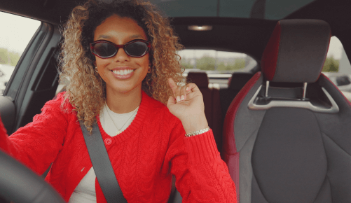 A woman with sunglasses on in the driver's seat of a car; How to get Car Finance on Benefits image