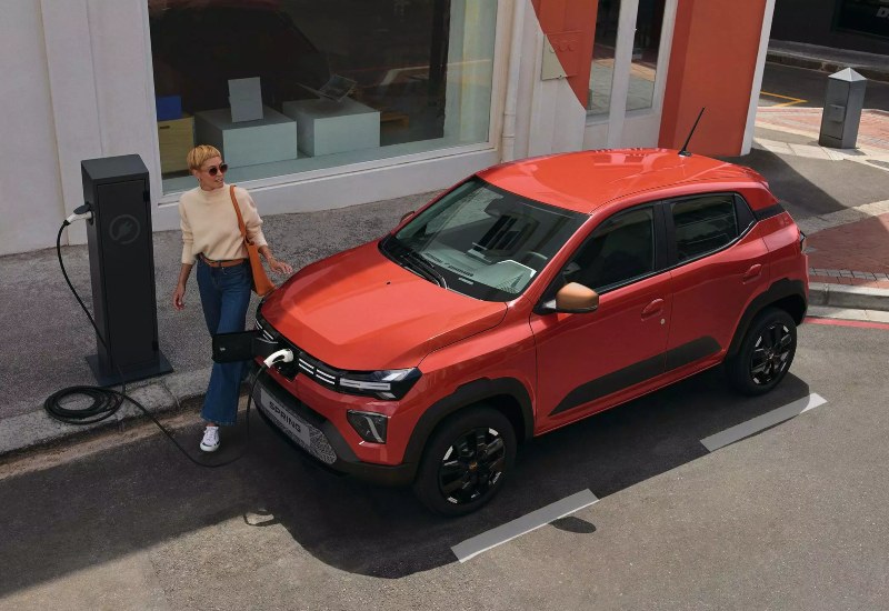 A woman at an on-street charging point with a used Dacia Spring electric car.