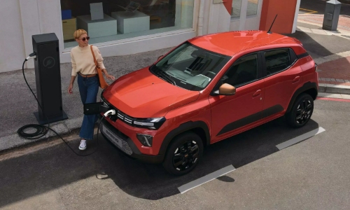 Used Dacia Spring Charging A woman at an on-street charging point with a used Dacia Spring electric car.