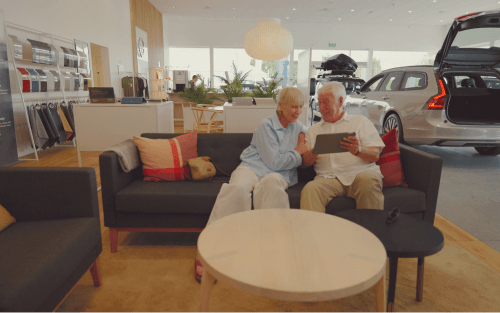 An older couple sit on a sofa in a car showroom; How does hire purchase car finance work image