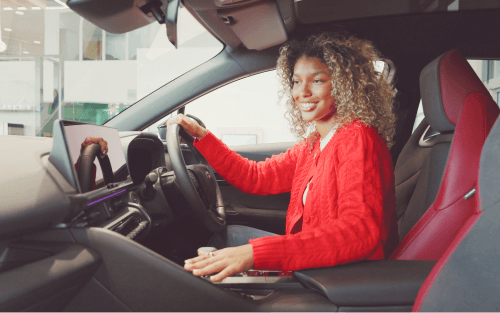 A woman sits in the driver's seat of a car; Pay as you go Car Finance for Bad Credit image