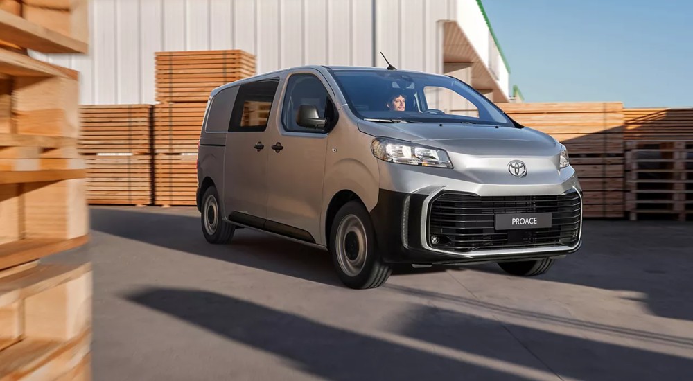 New Toyota Proace van driving through warehouse with stacked wooden pallets.