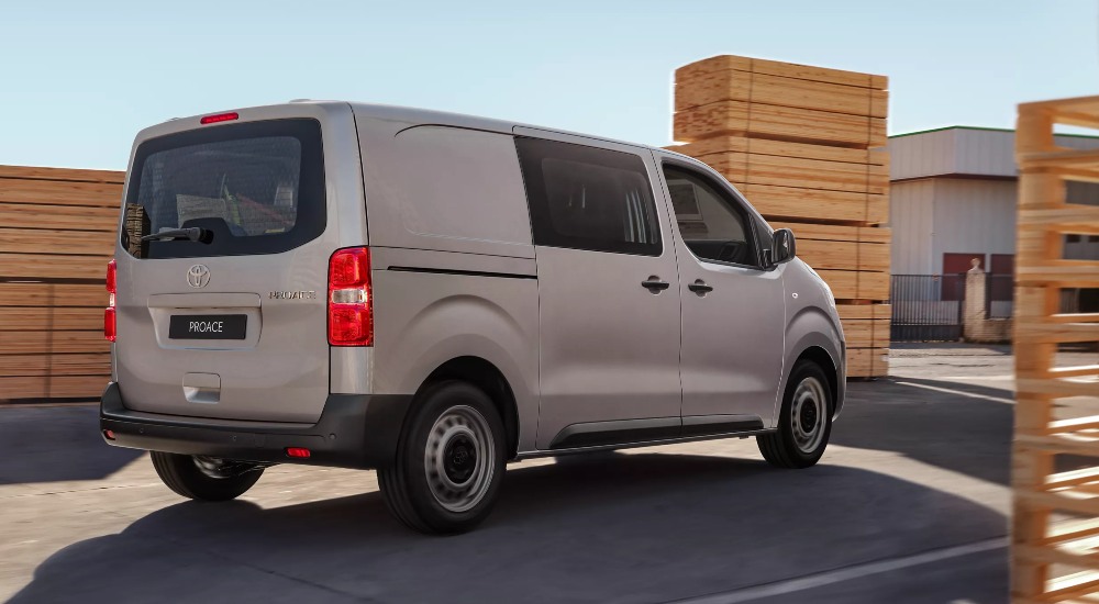 New Toyota Proace van in warehouse yard, with a large rear door and durable build.
