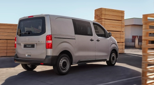 New Toyota Proace van in warehouse yard, with a large rear door and durable build.