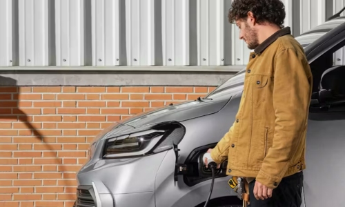 The new Toyota Proace Electric van in silver, charging at the front with a man plugging in the cable.