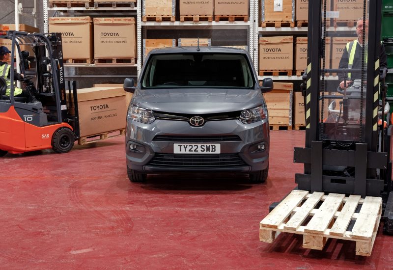 Used Toyota Proace City van in a warehouse with forklifts and crates, ideal for commercial logistics.