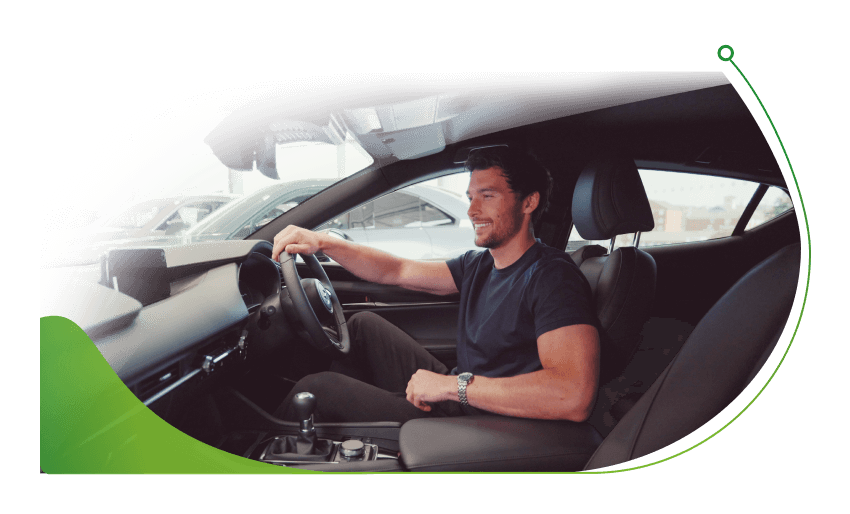 A man sits in the cabin of a new car; PCH car leasing deals image