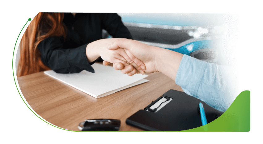 Two people shake hands at a desk; About Moneybarn image