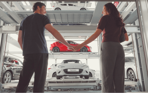 Two people hold hands in a car dealership; Who can be a guarantor image
