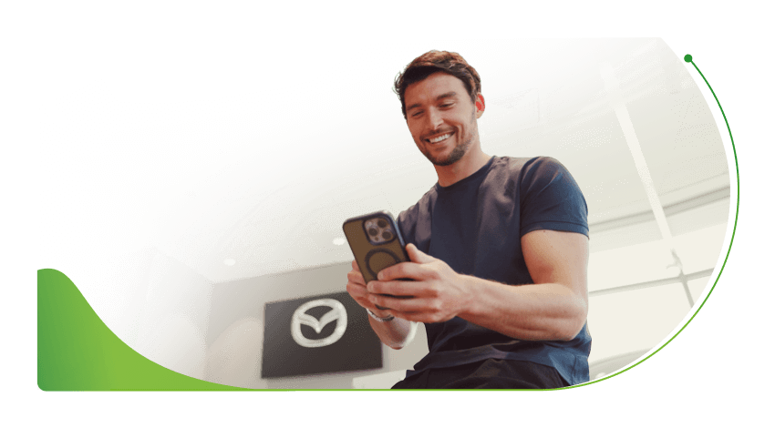 A man looks at a phone in a car dealership; How to improve your credit score image