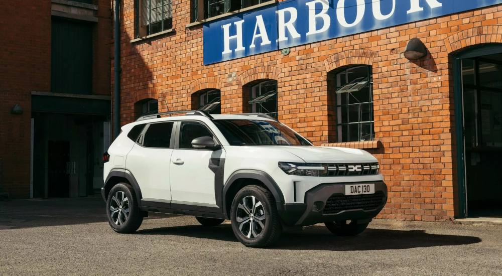White Dacia Duster Cargo parked outside a brick industrial building.