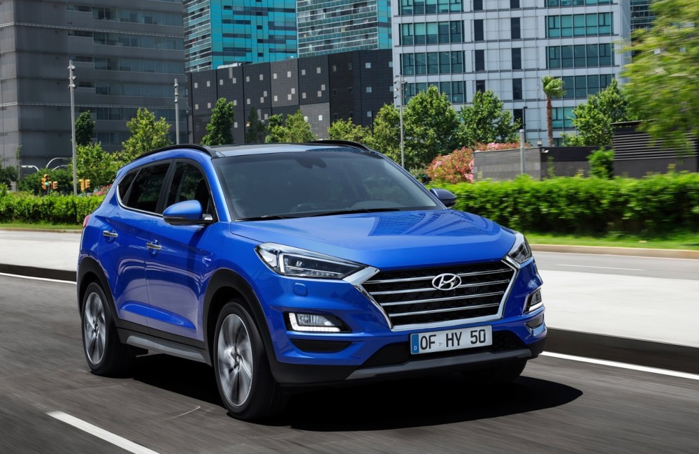 A blue Hyundai TUCSON used car driving at speed down a city road