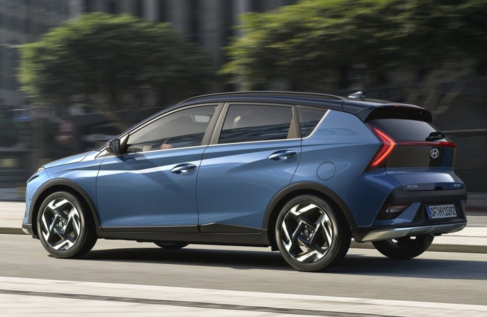 Side profile of a new Hyundai BAYON moving at speed within a city