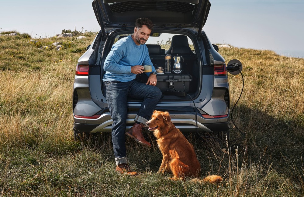 A person and their dog sat in the boot of a BYD SEAL U DM-i drinking homemade coffee