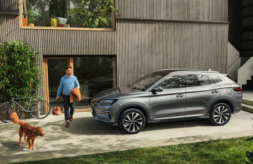 A person and their dog stepping outside their home to go on a trip in their new BYD SEAL U DM-i