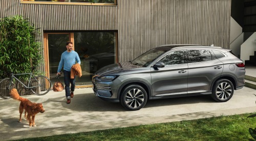 A person and their dog stepping outside their home to go on a trip in their new BYD SEAL U DM-i