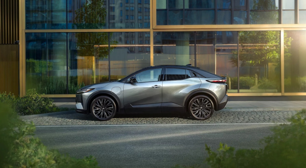 New Toyota C-HR+ Excel trim parked among greenery, showing 20-inch alloy wheels and elevated ride height.
