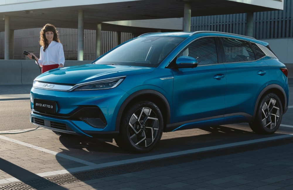 BYD ATTO 3 about to be plugged in to charge by a person in formal attire