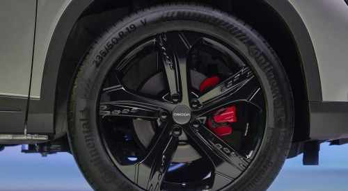 A close up of a new OMODA black alloy wheel, featuring a red brake caliper and continental tyres