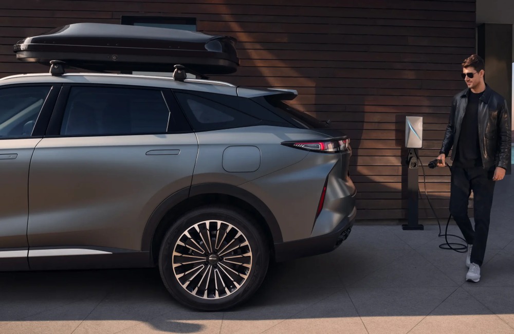 Person in casual attire holding a charger in prep to charge up a new OMODA hybrid car