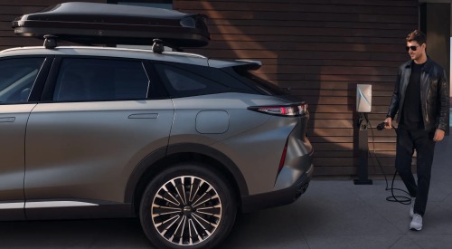 Person in casual attire holding a charger in prep to charge up a new OMODA hybrid car