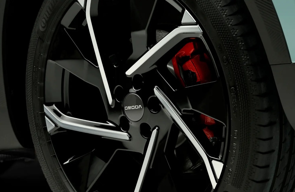 Close-up view of alloy wheels, boasting the OMODA branding, unique designs, and red brake calipers.